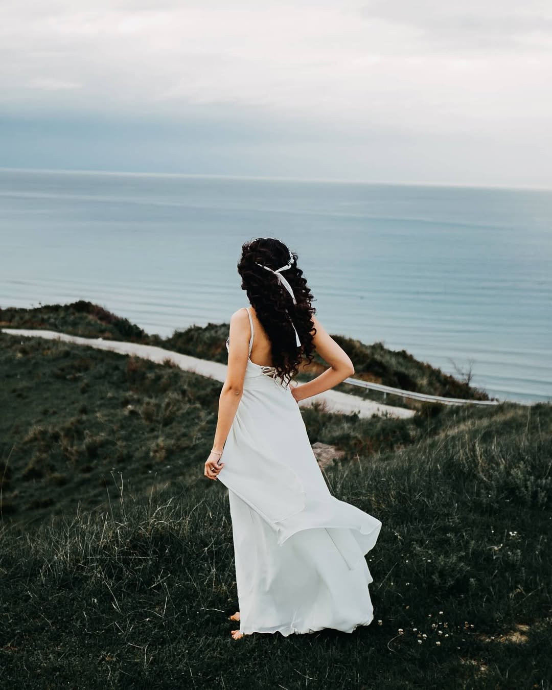 Bride overlooking the sea from the clifftops of Cape of Rodon
